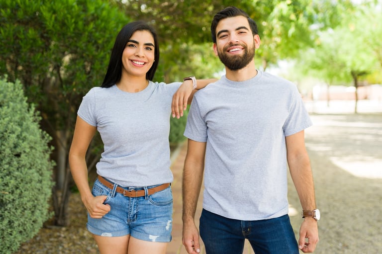 Good looking young hispanic couple wearing plain gray t-shirts standing together in a park