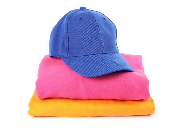 Blue baseball cap and stack of folded t-shirts isolated on white