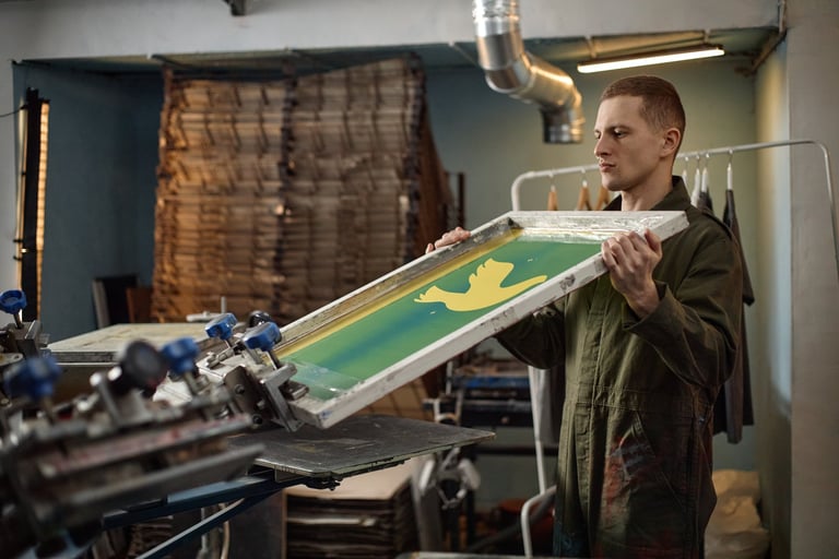 Screen printing press printing design onto fabric in workshop