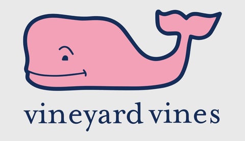 Pink whale illustration with navy outline and Vineyard Vines text below on gray background