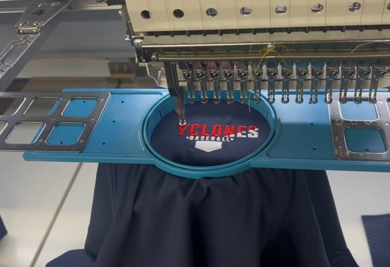 Industrial embroidery machine with blue frame stitching red logo onto black fabric